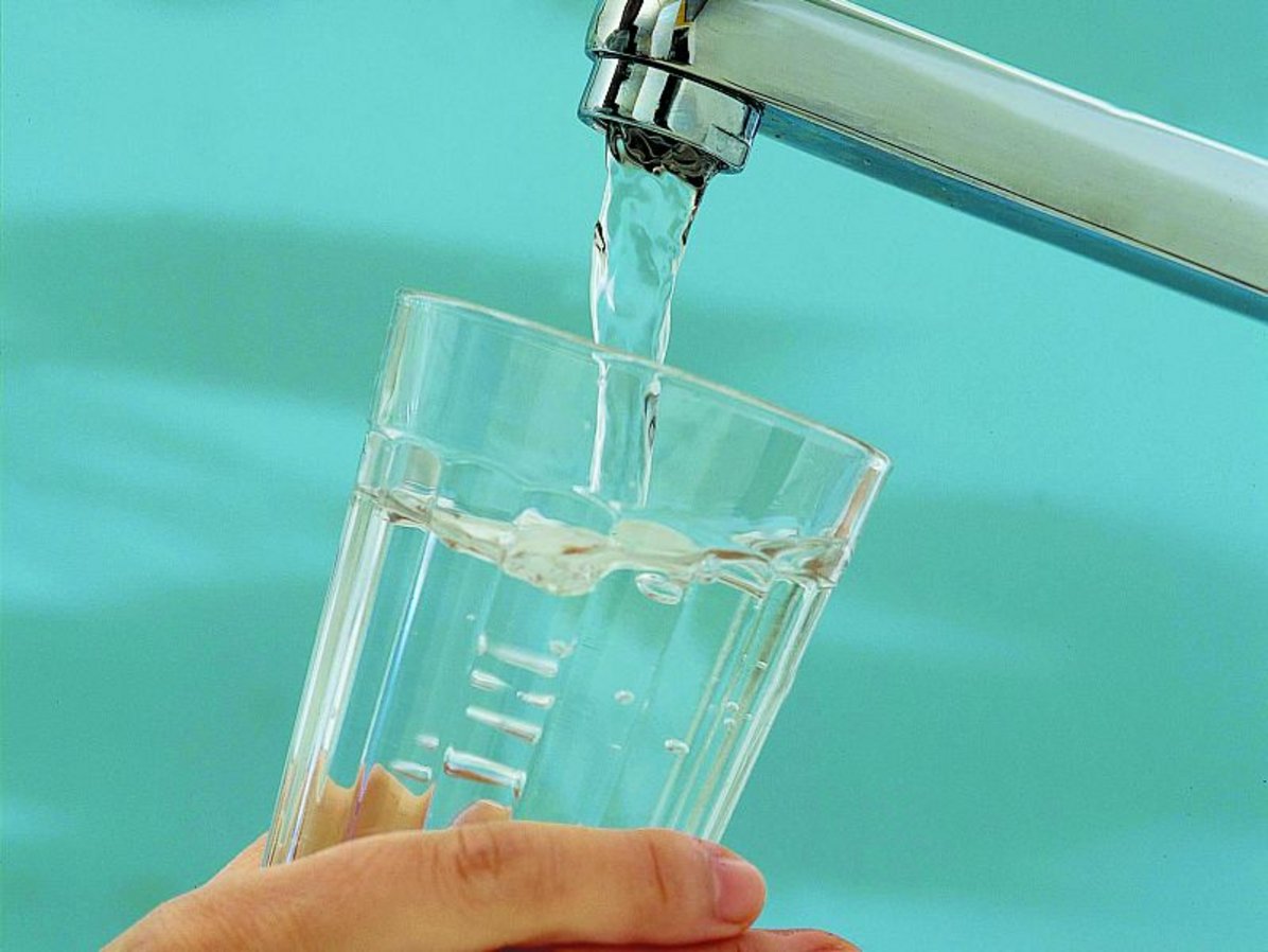 Glas wird am Wasserhahn mit Wasser aufgefüllt